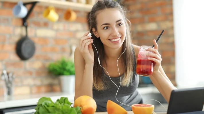 Cô gái cười, tay cầm ly sinh tố giàu protein.