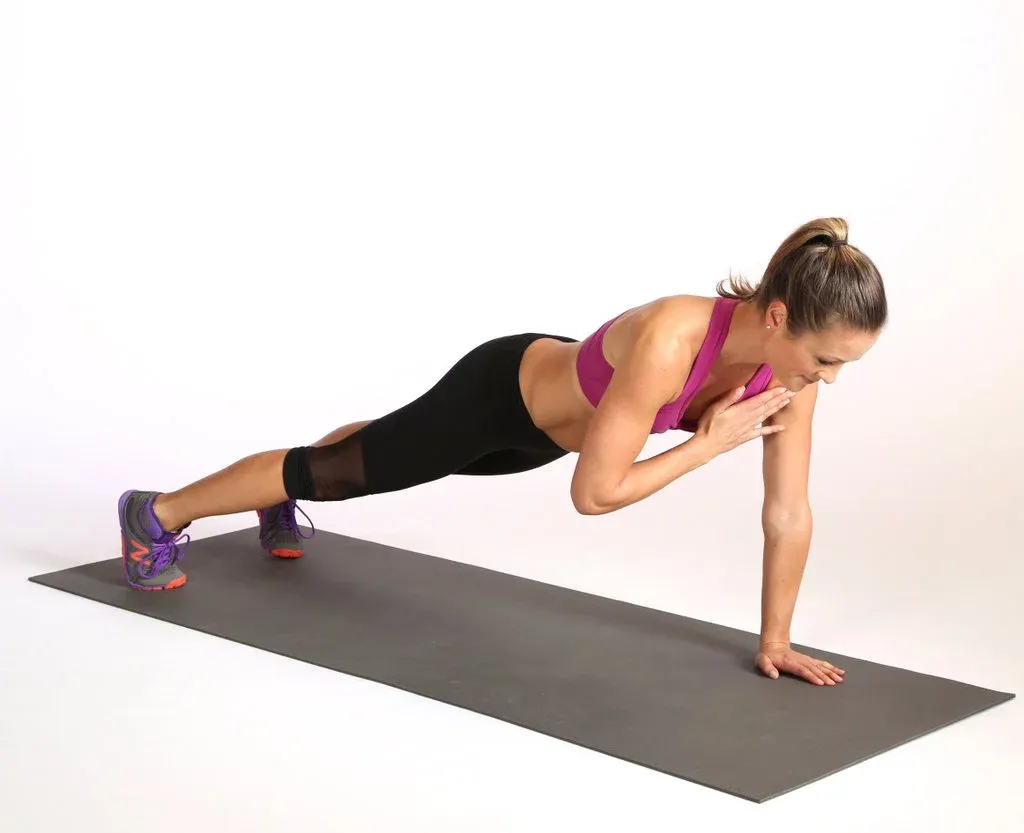 Cô gái thực hiện bài tập Plank chạm vai.
