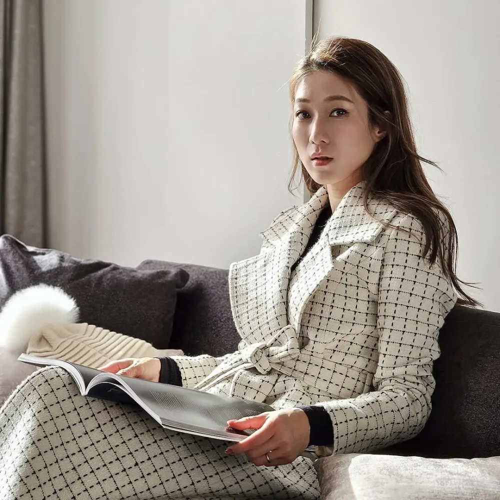 Nữ diễn viên ngồi trên sofa và cầm cuốn tạp chí.