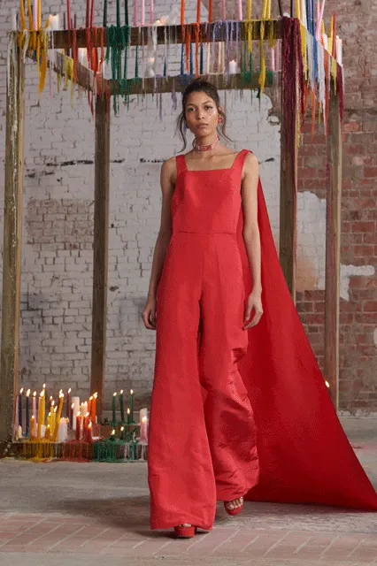 Bên cạnh những chiếc váy cape thịnh hành trong thời gian vừa qua, Assouline phối hợp cape trên bộ jumpsuit ống rộng màu cam đỏ đơn giản nhưng sang trọng.