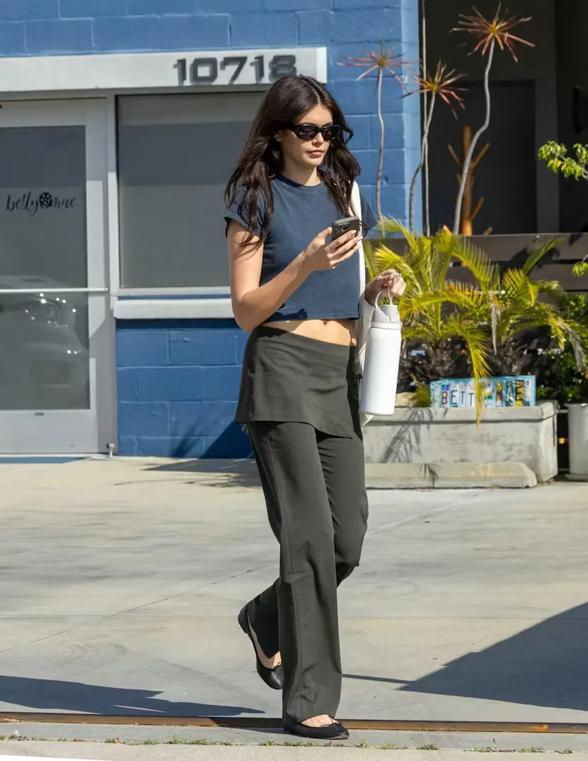 Kaia Gerber thoải mái dạo phố với giày bệt và quần peplum, đặc biệt kết hợp cùng áo croptop giúp tôn eo.