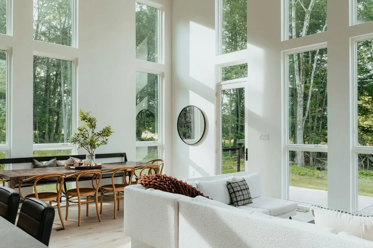 Phòng khách phong thủy có concept màu trắng và cửa kính lớn nhìn ra rừng cây