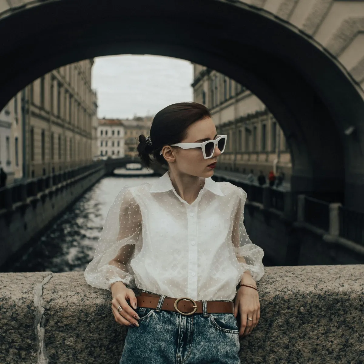 cố gái đeo kính râm đứng trên cầu