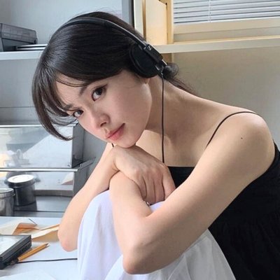 cô gái đeo tai nghe đang ngồi khoanh hai tay lên đầu gối