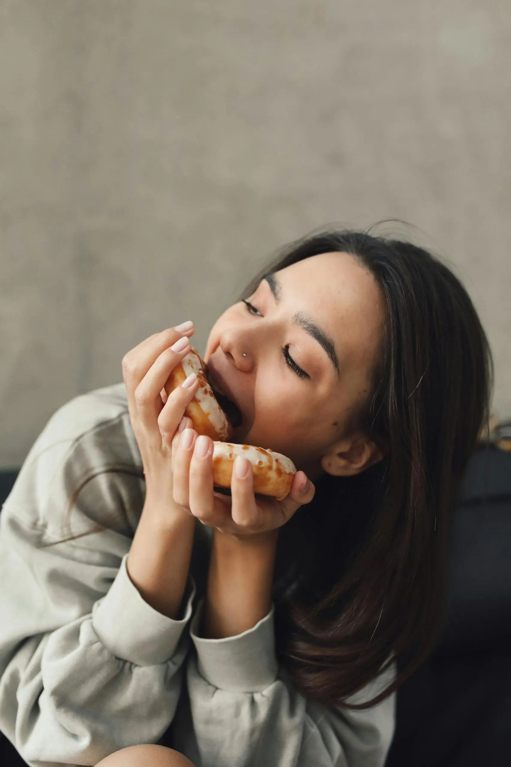 Cô gái ăn donut trong tâm trạng thoải mái, minh họa cho thói quen ăn uống theo cảm xúc khi căng thẳng
