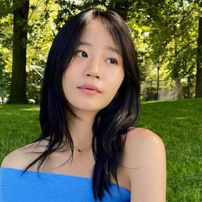 gen z - cô gái châu Á có tóc đen dài, mặc áo hở vai màu xanh dương và chân váy trắng để đi picnic trong công viên