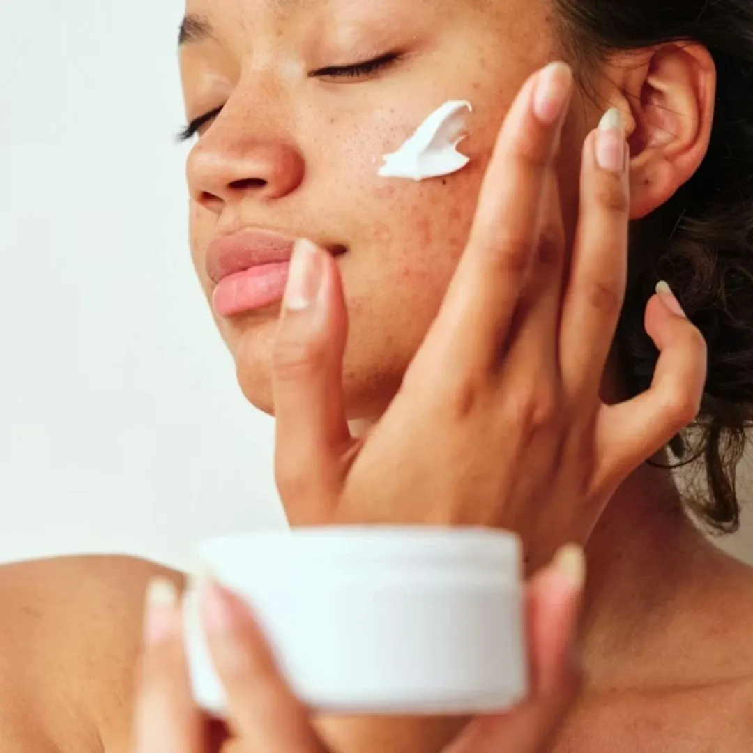 Cô gái thoa kem chống nắng trước khi trang điểm