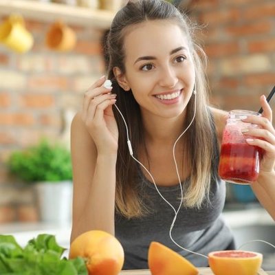 Cô gái cười, tay cầm ly sinh tố giàu protein.