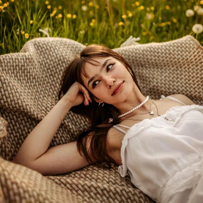 cô gái gác tay nằm trên thảm trên bãi cỏ hoa vàng