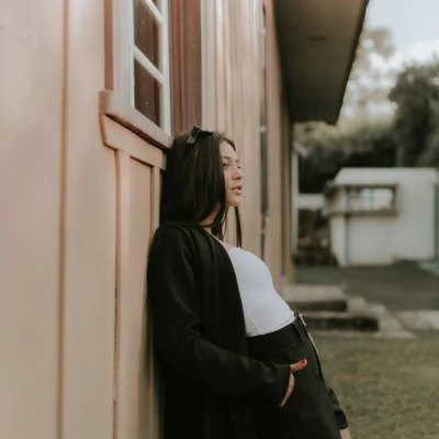 cô gái mặc áo đen tựa vào tường elle