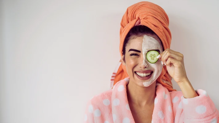 cô gái đội khăn tắm và đắp dưa leo một bên mặt để giảm quầng thâm mắt