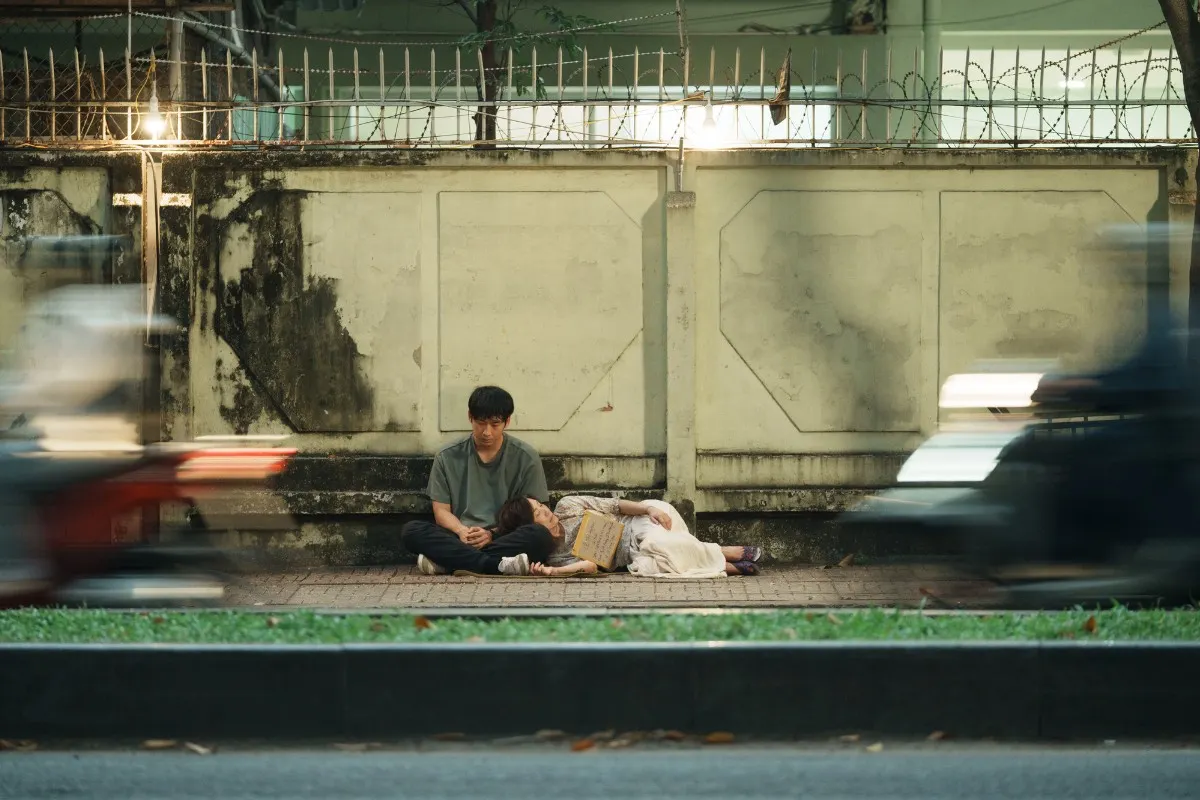 Tuấn Trần và Hồng Đào trong một phân cảnh nằm bên vỉa hè trong Mang Mẹ Đi Bỏ