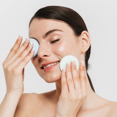 cô gái cười nhẹ đặt hai tay lên mặt