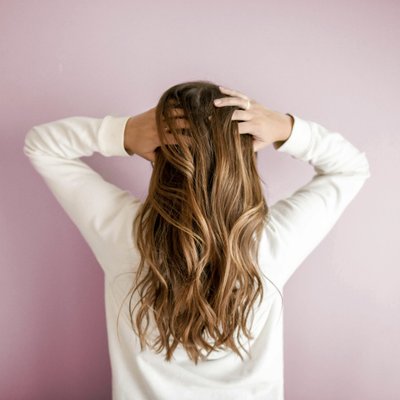 Cô gái tay đang ôm đầu với mái tóc dài màu vàng nâu - dưỡng tóc bằng dầu dừa