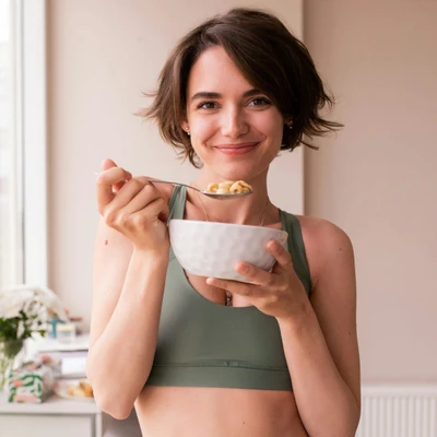 Người phụ nữ ăn ngũ cốc và trái cây – nguồn carbohydrate giúp bổ sung năng lượng cho cơ thể, tránh cảm giác thèm ăn truớc kỳ kinh