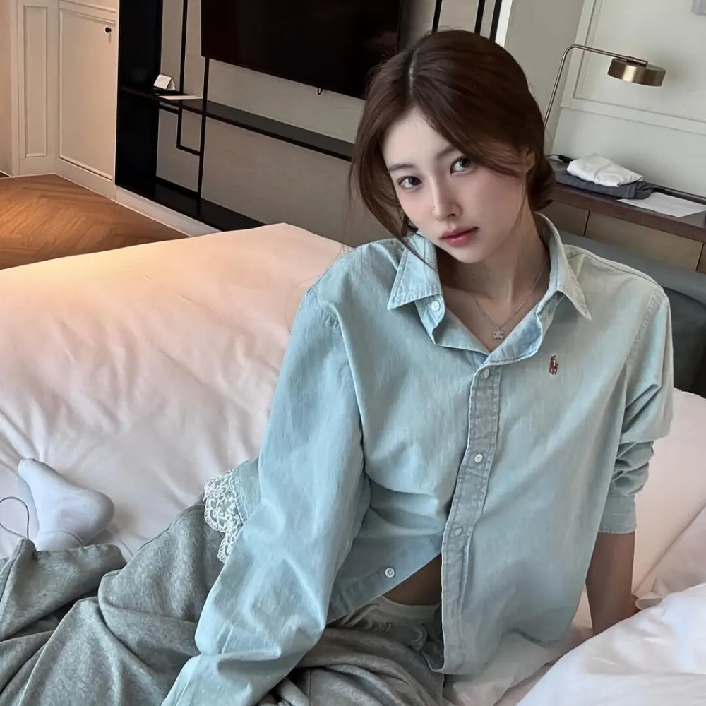 Cô gái mang áo sơ mi xanh ngọc ngồi trên giường