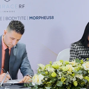 người đàn ông và người phụ nữ trong trang phục chỉn chu đang ngồi ký kết