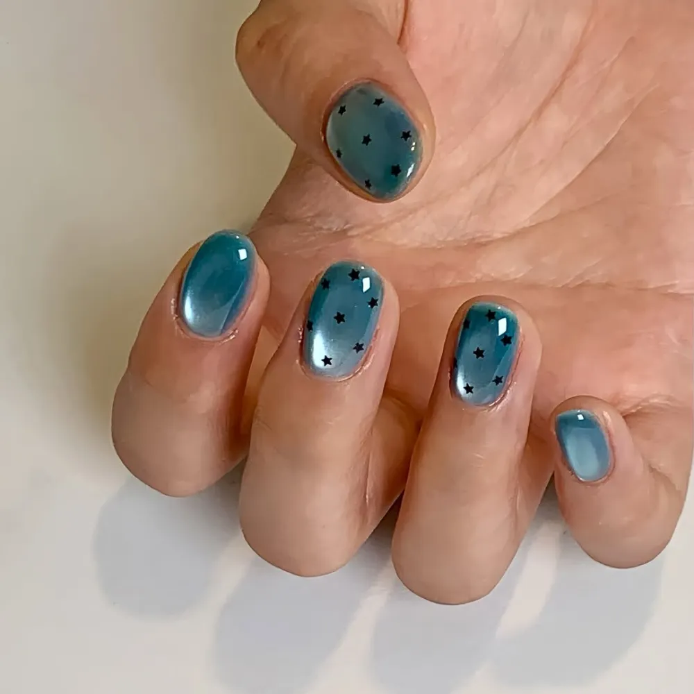 Bàn tay với kiểu nail mắt mèo màu xanh cùng họa tiết ngôi sao