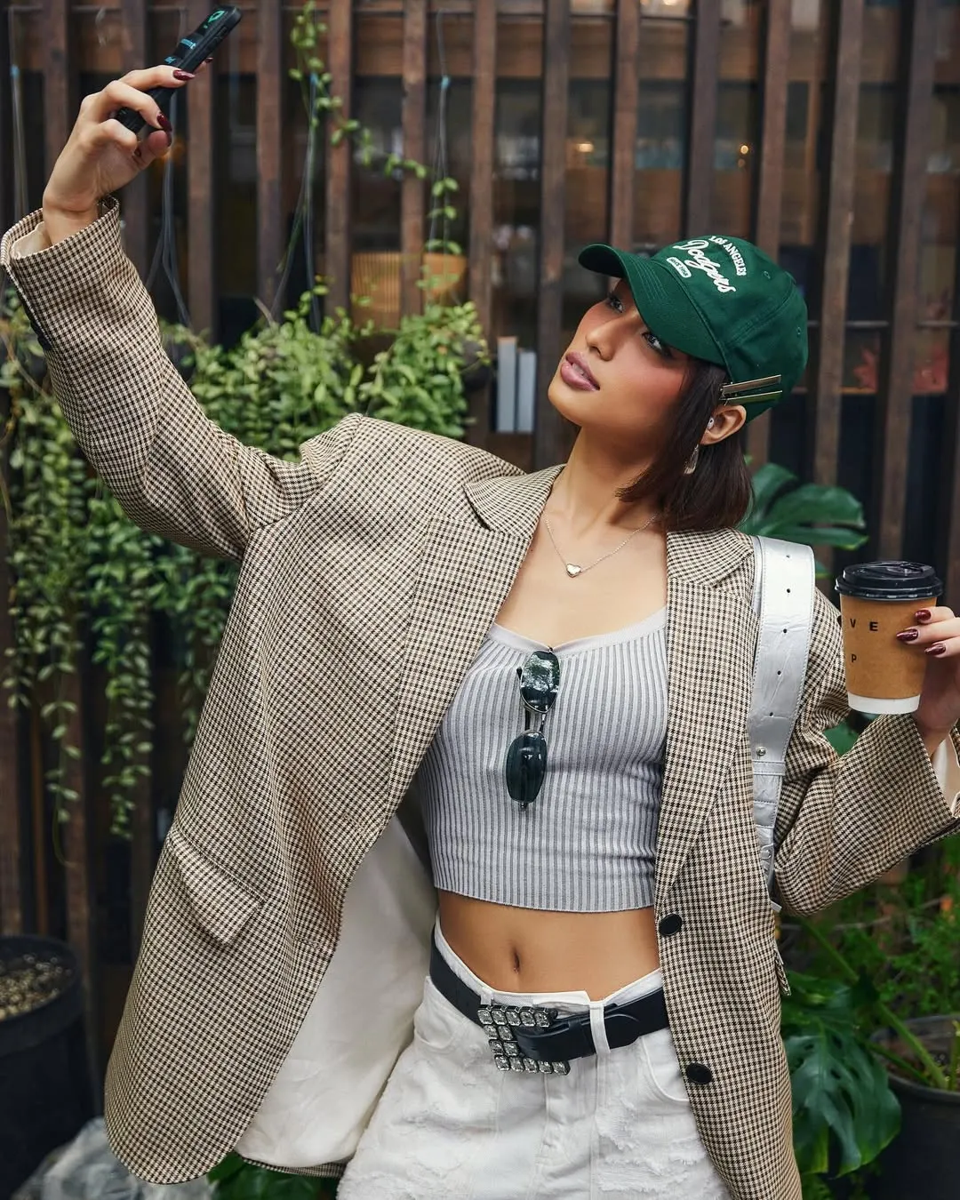 Một chiếc mũ lưỡi trai kaki màu xanh rêu không chỉ che đi phần chân tóc bết mà còn nâng tầm set đồ blazer.