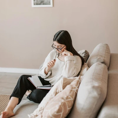 cô gái tóc đen mặc áo trắng ngồi trên sofa lập kế hoạch để thành công