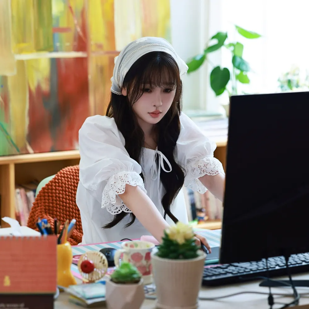 Ngu Thư Hân mang đầm trắng ngồi trước bàn máy tính.