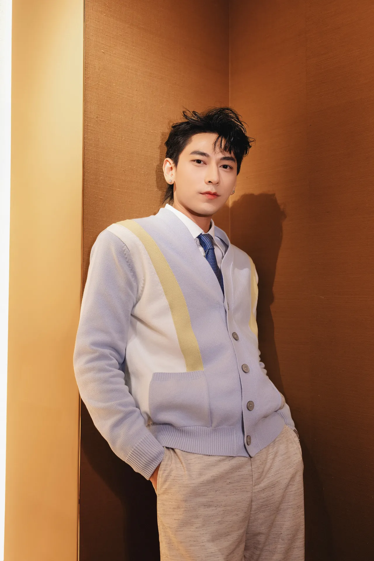 Isaac xuất hiện tại sự kiện trong chiếc áo cardigan màu xanh vàng nhẹ nhàng mặc ngoài sơ mi trắng đi cùng quần tây sáng màu.