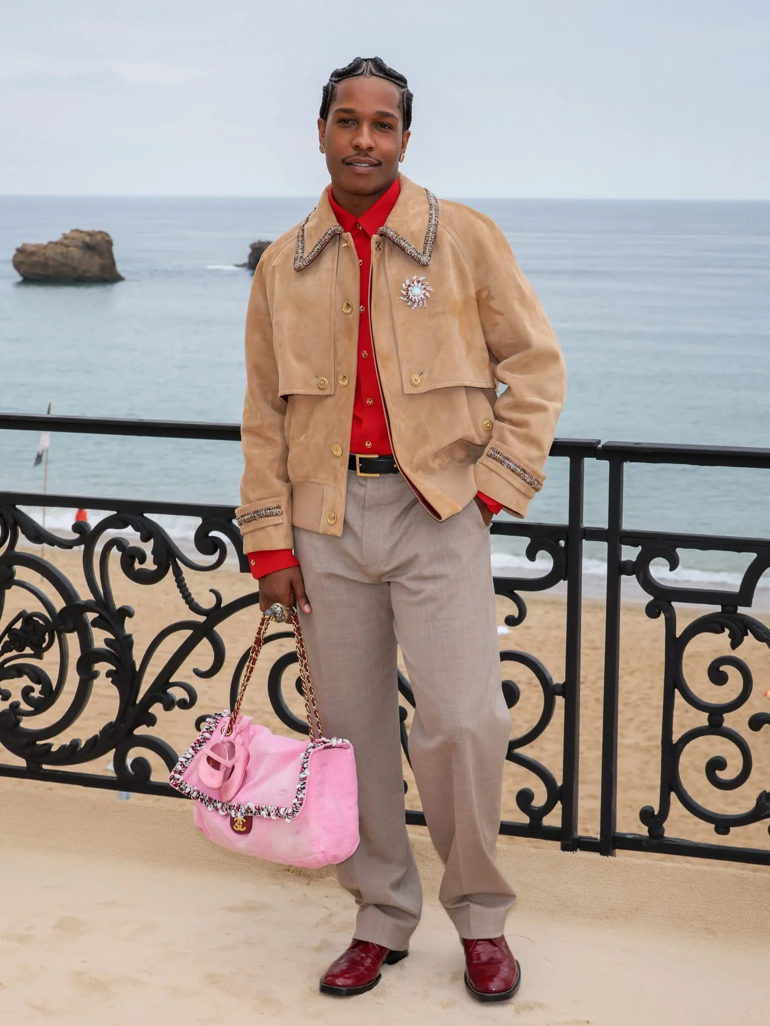 A$AP Rocky lựa chọn jacket dáng rộng và quần suông, giữ bảng màu trung tính. Điểm nhấn nằm ở chiếc túi Chanel được gắn đôi giày ballet nhỏ dành cho con gái.