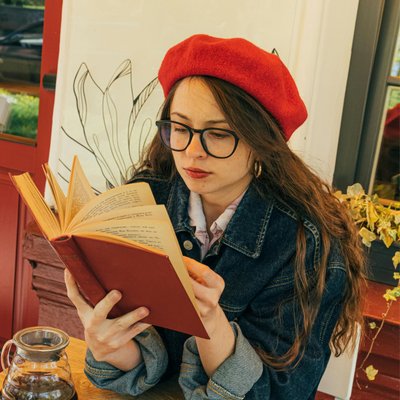 cô gái đội nón đỏ đọc sách ở quán cà phê một mình