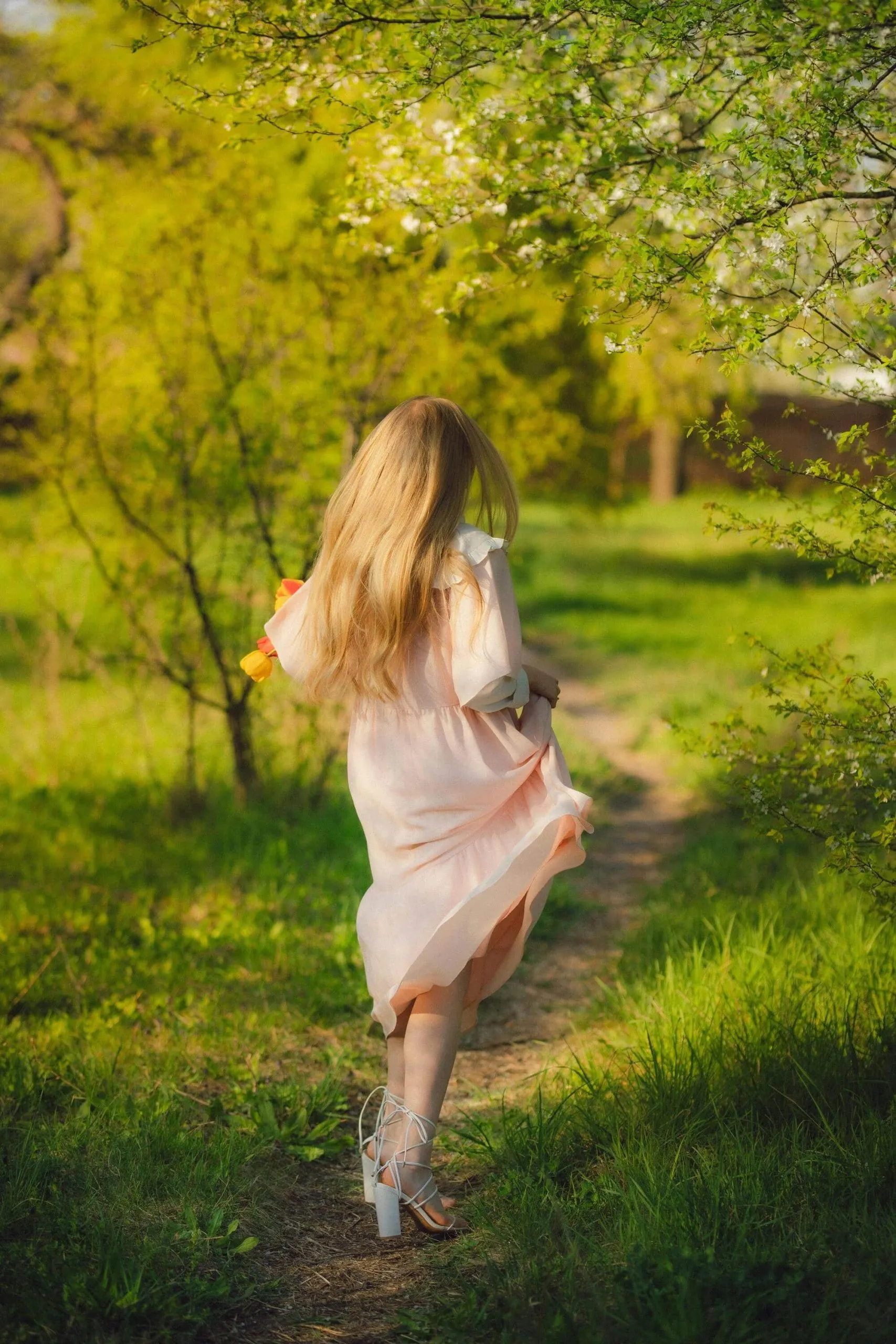 cô gái mặc váy hồng chạy trên con đường đầy cỏ