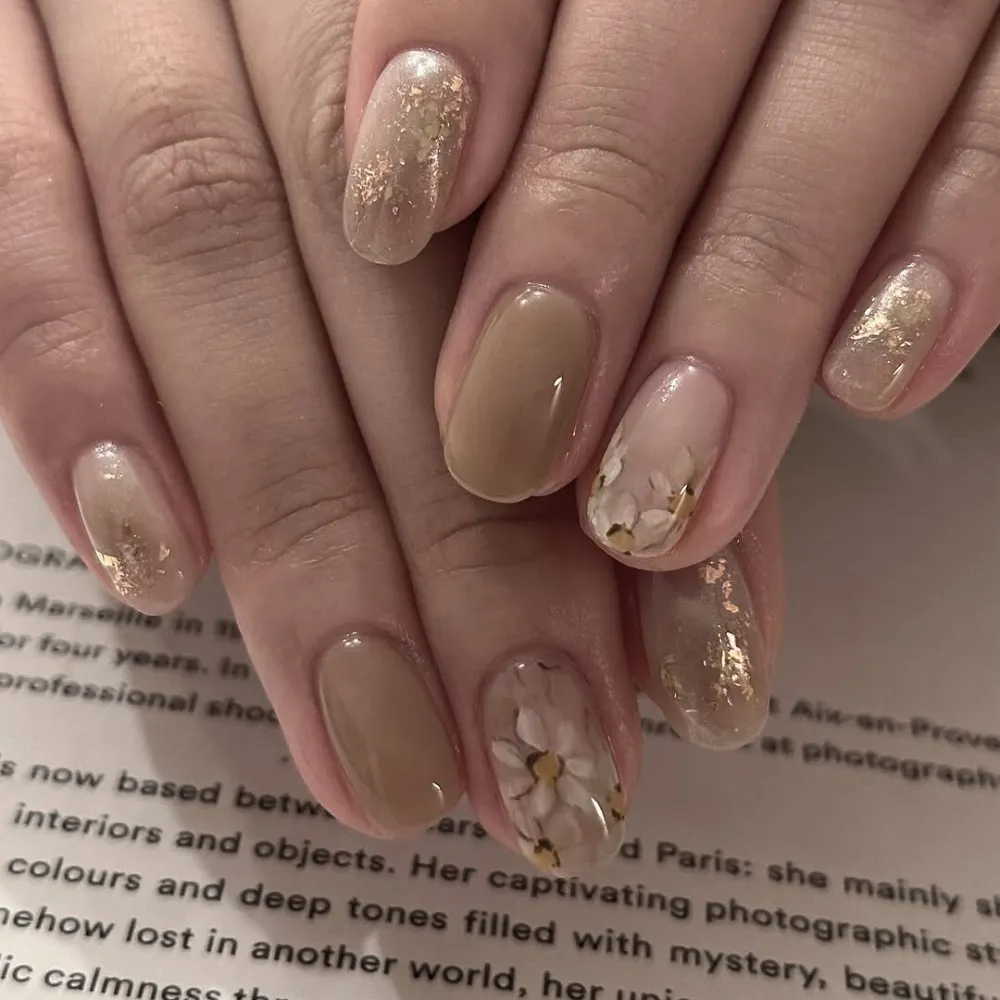 đôi tay với kiểu nail màu nâu trà sữa cùng họa tiết bông hoa