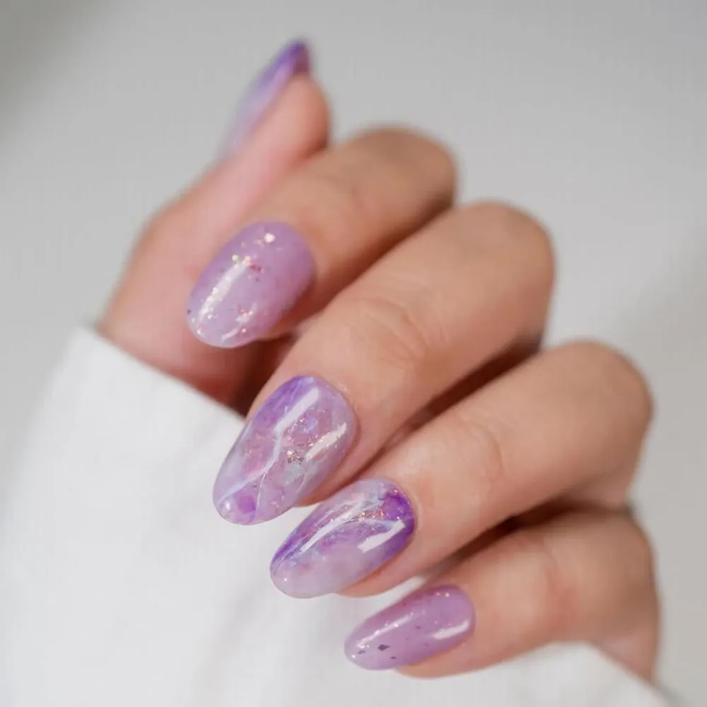 Hình ảnh mẫu nail màu tím violet với hiệu ứng vân đá và đính kết ánh kim.