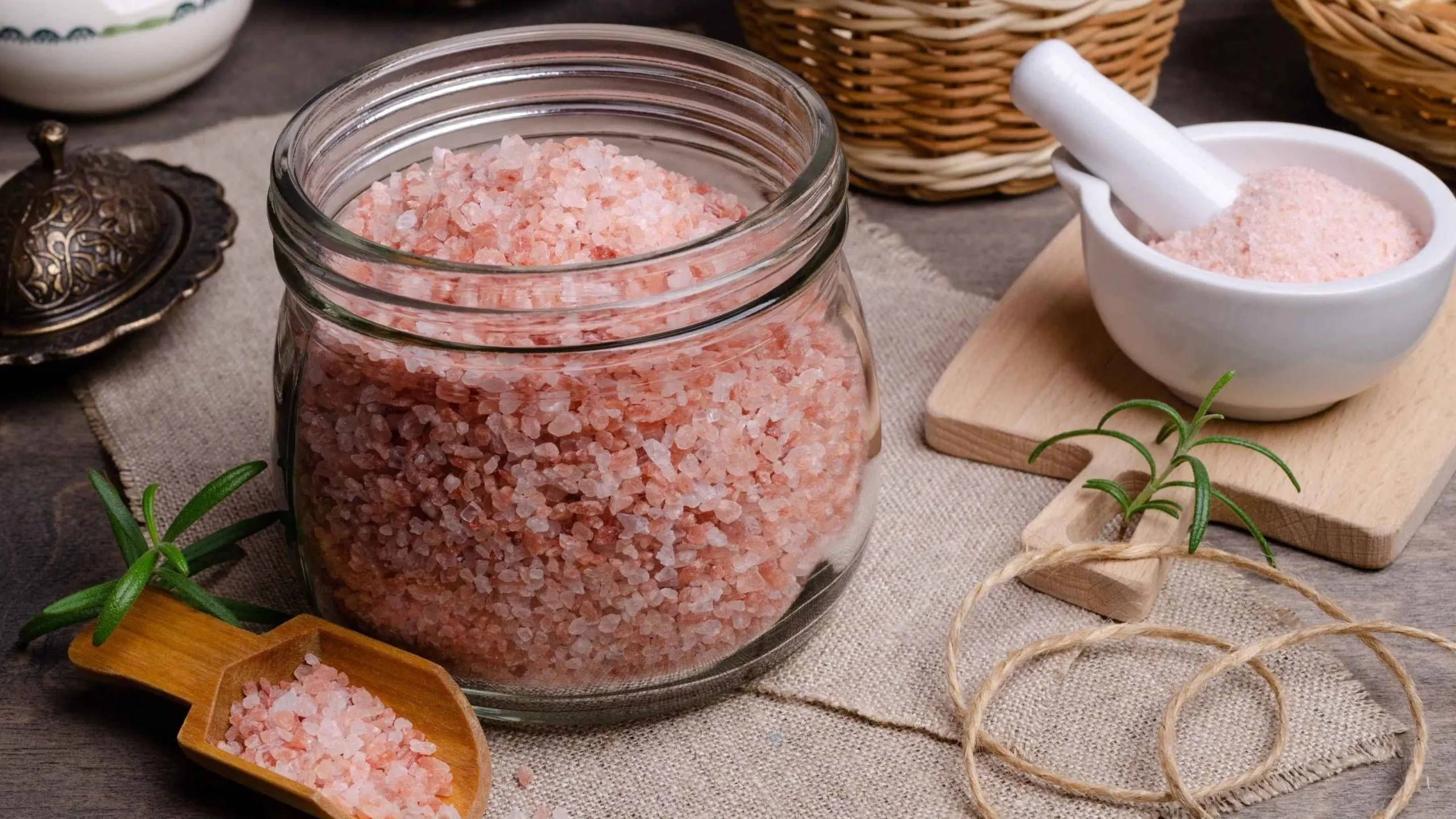 Muối hồng Himalaya đựng trong lọ thủy tinh và chén sứ.