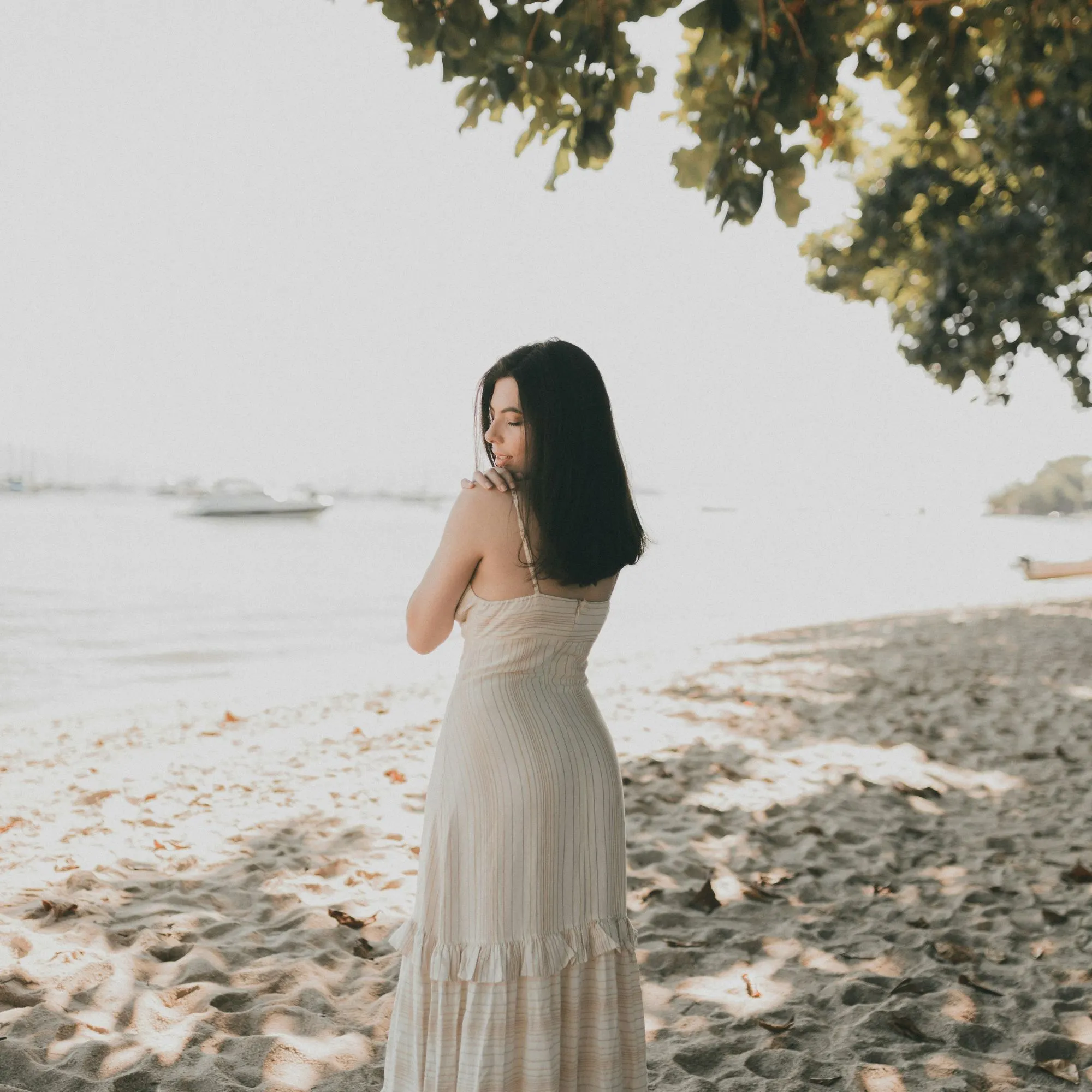 cô gái mặc váy trắng đứng bên bờ biển