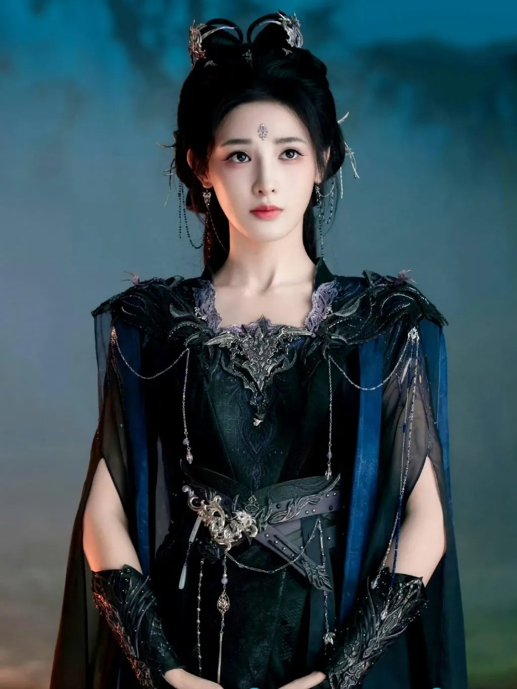 Mái tóc buộc cao cùng áo choàng tím sẫm tạo diện mạo vừa mạnh mẽ vừa quyến rũ.