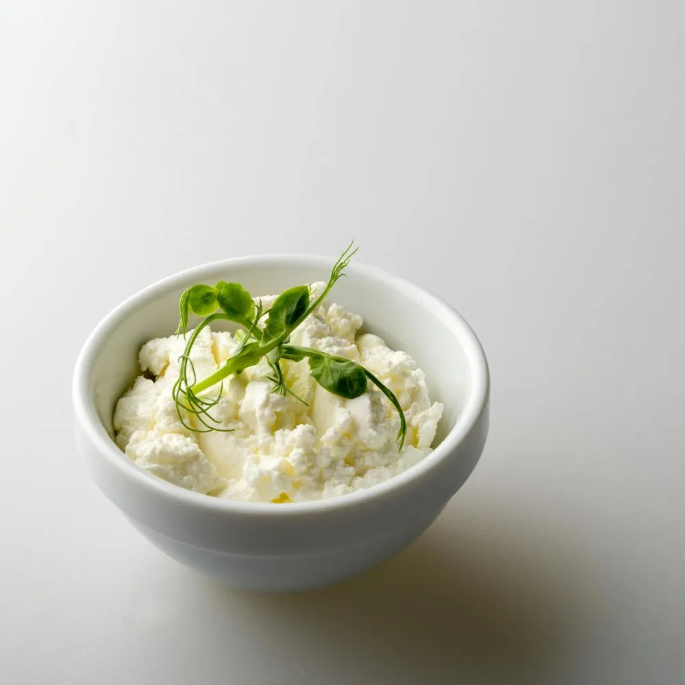 Phô mai tươi mềm mịn trong bát trắng – nguyên liệu giàu đạm cho sinh tố