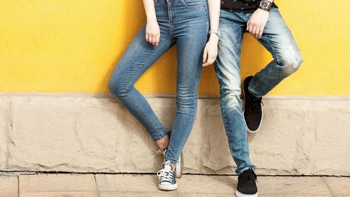 quần jeans nam và nữ đứng trước bức tường vàng