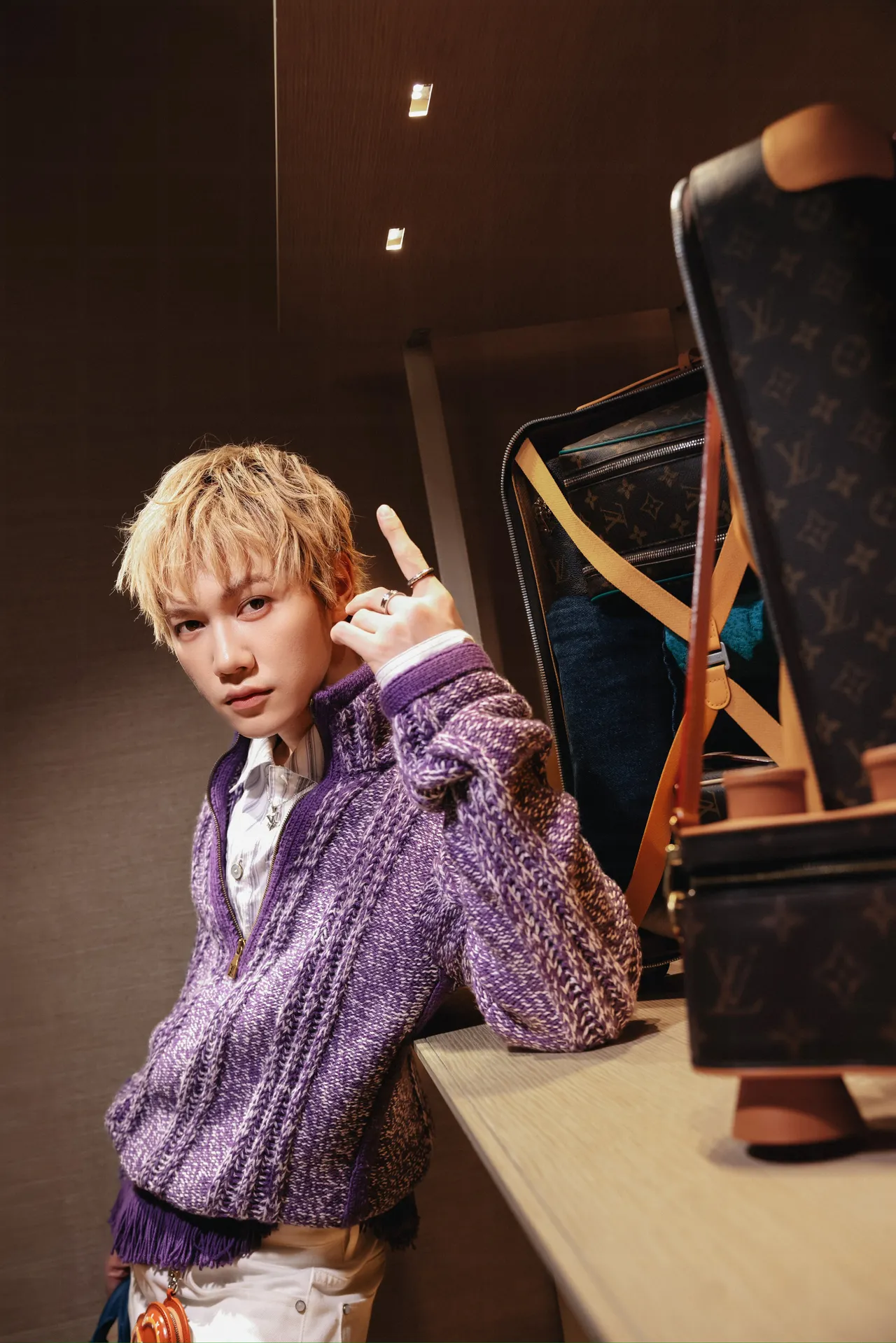 JSOL kết hợp áo len kéo khóa họa tiết màu tím cùng quần trắng, điểm nhấn là chiếc túi Speedy màu xanh loang và phụ kiện charm hình bánh pretzel.