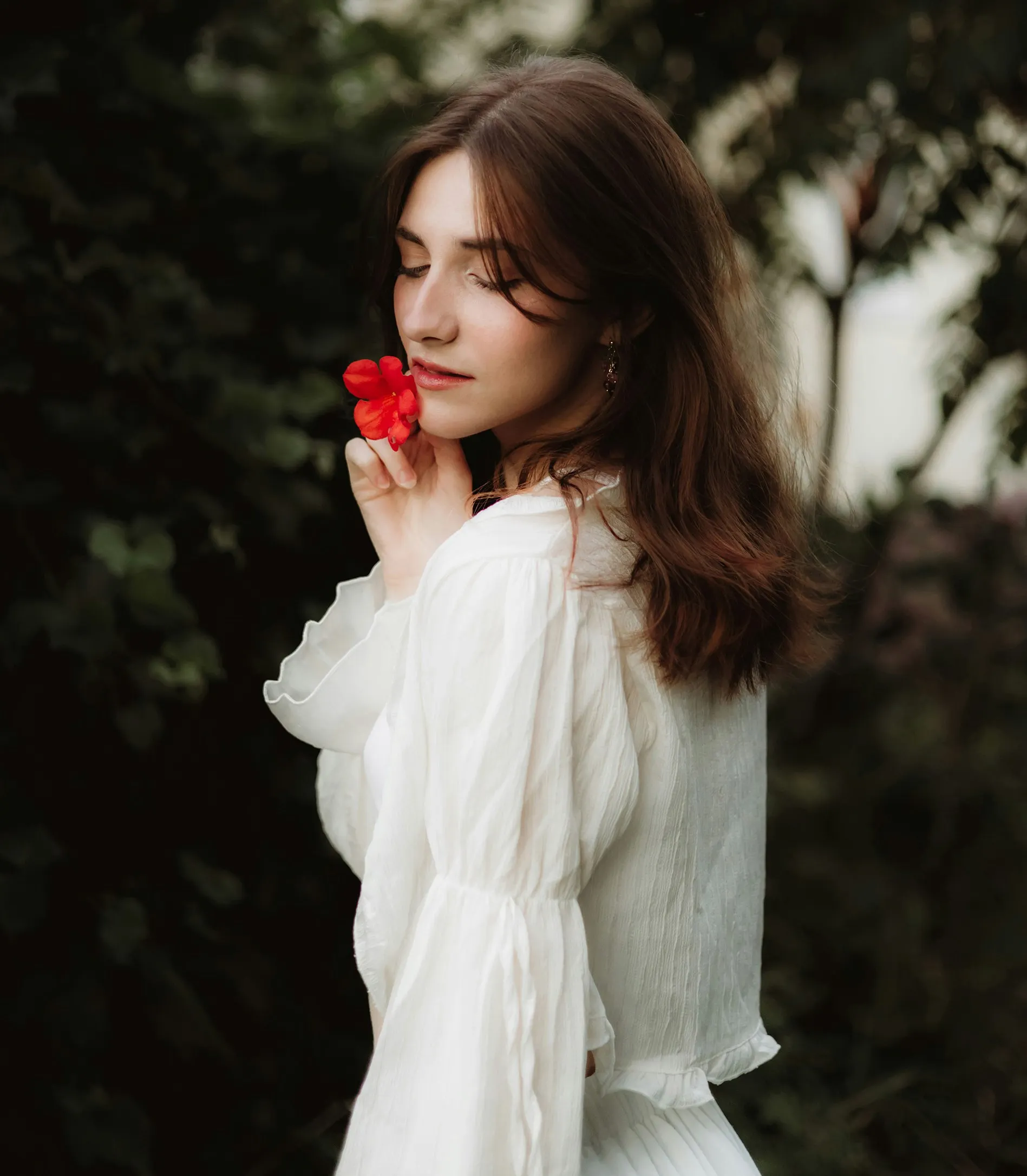 cô gái mặc đầm trắng cầm bông hoa màu đỏ