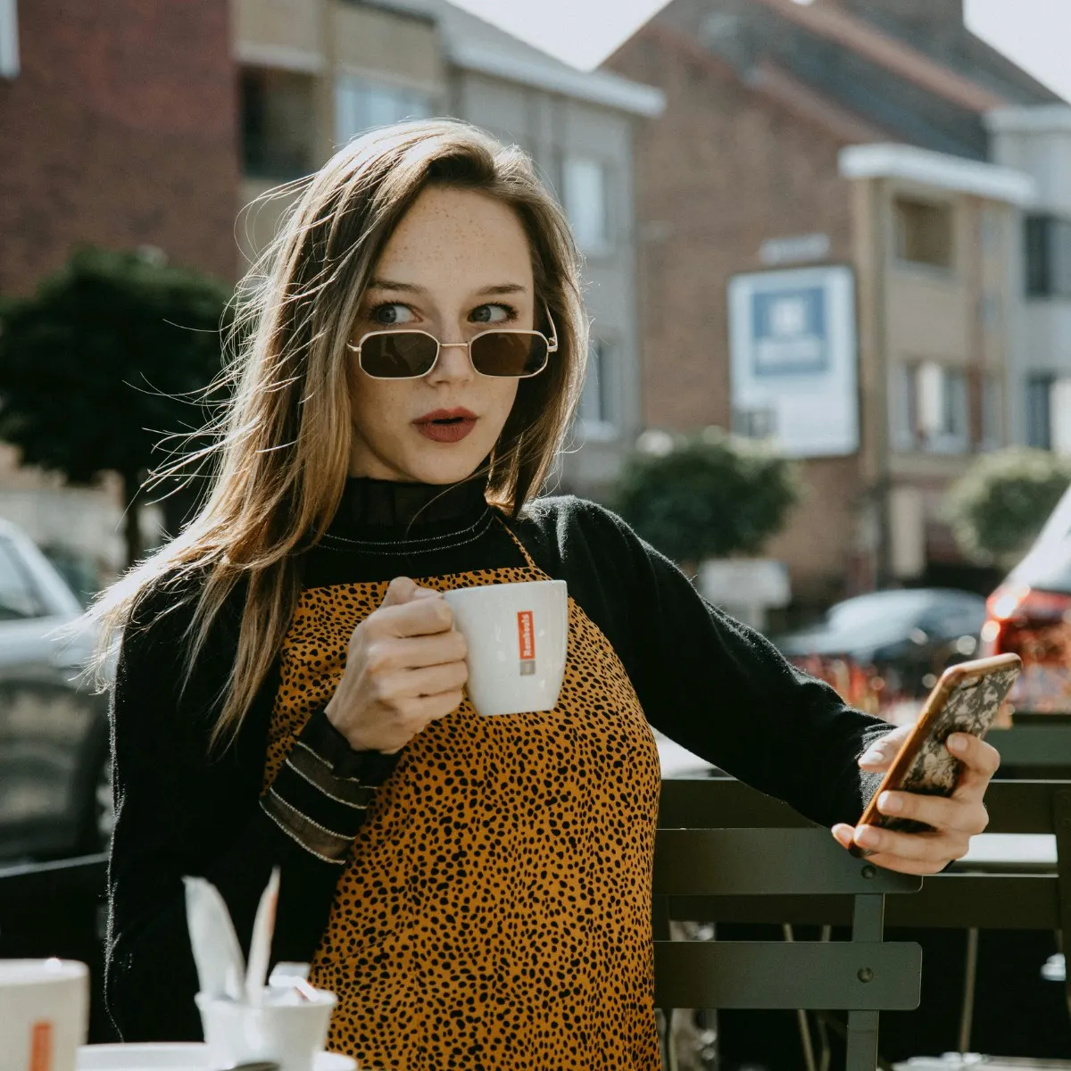 cô gái tóc vàng dài đeo kính mát ngồi uống cà phê trên phố