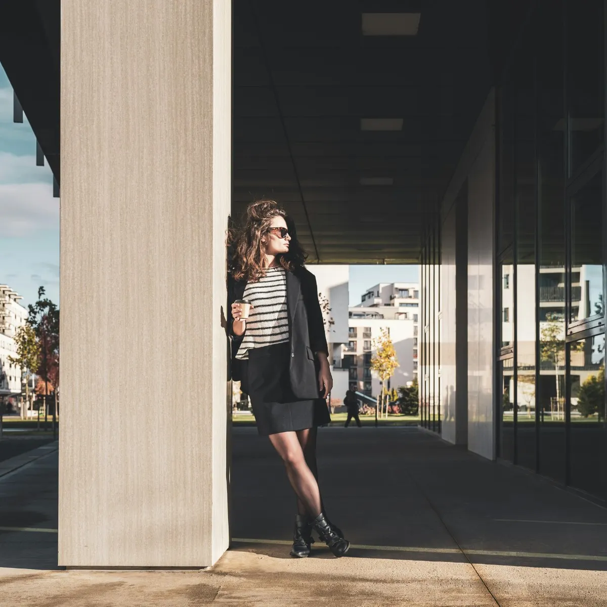 Cô gái cầm cốc cà phê đứng dựa vào cột muốn thay đổi công việc