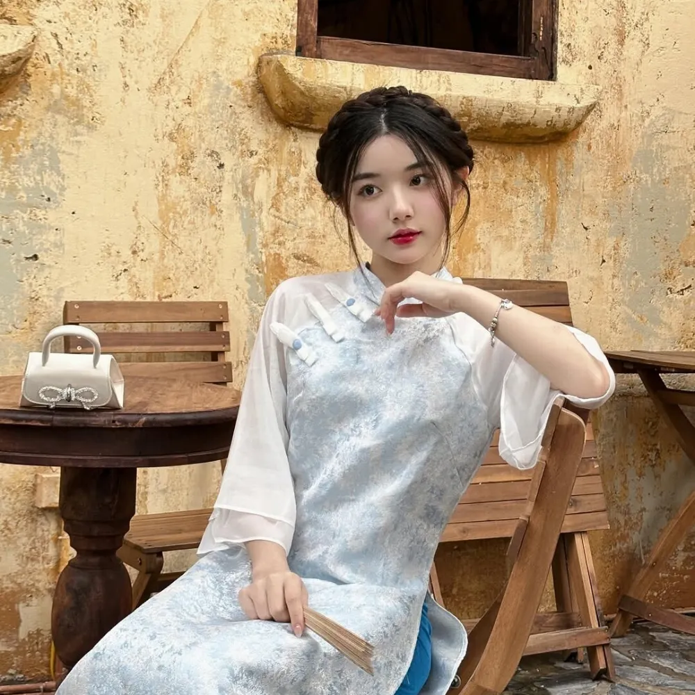 Cô gái mang áo dài xanh dương nhạt ngồi trên ghế