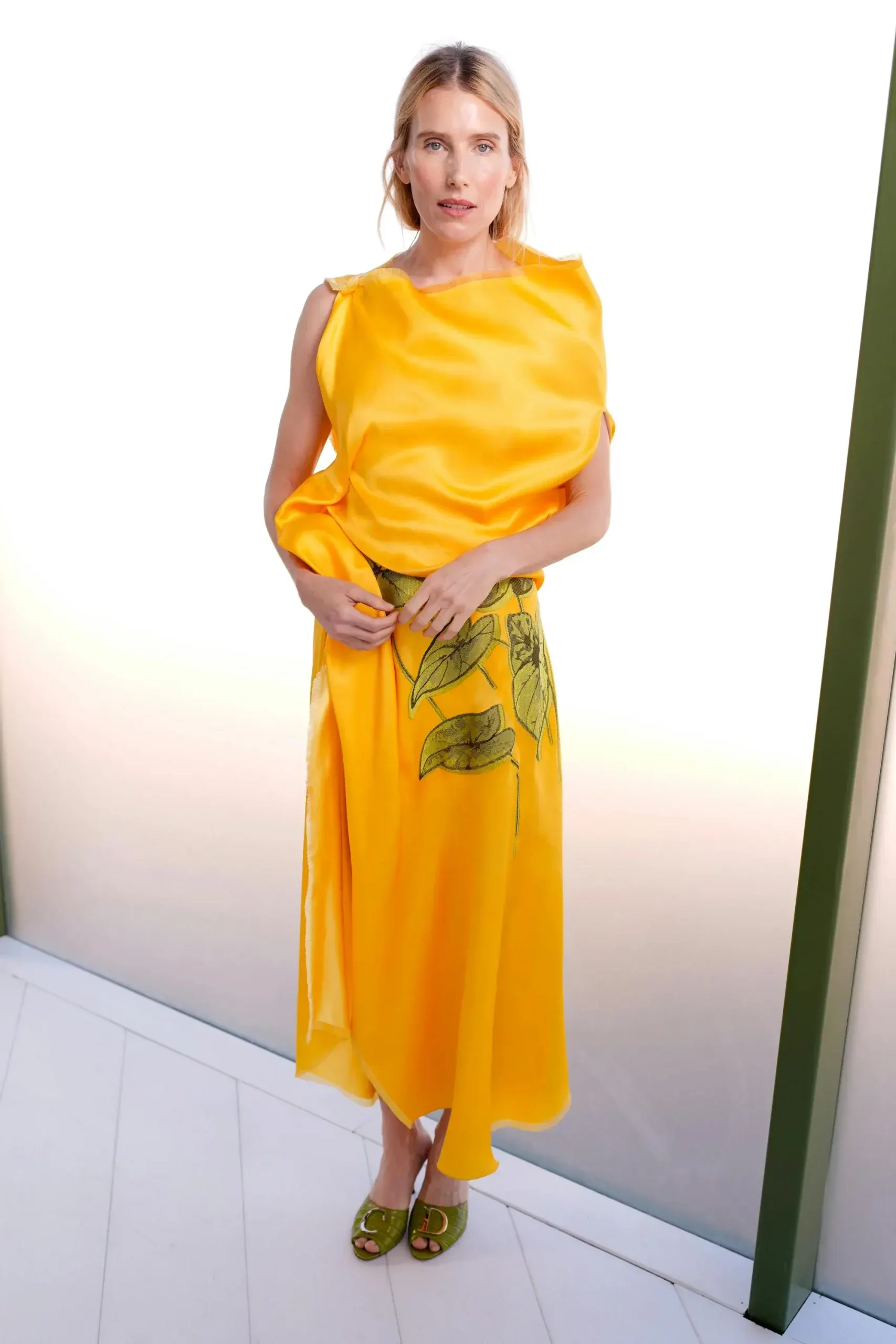 Dree Hemingway diện thiết kế đầm lụa màu vàng rực rỡ với chi tiết in hình lá sen xanh ở chân váy, đi cùng đôi dép cao gót hở mũi đồng màu.