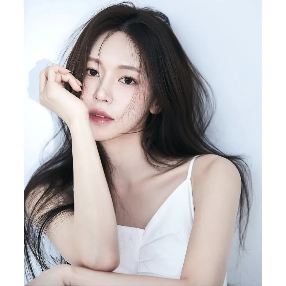 Cô gái với làn da đều màu, trắng sáng ngồi chống tay lên cằm