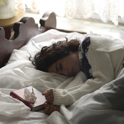 cô gái nằm nghiêng ngủ bên cạnh có quyển sách