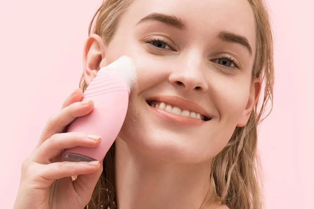 Người phụ nữ dùng máy rửa mặt làm sạch da - chăm sóc da sau nặn mụn