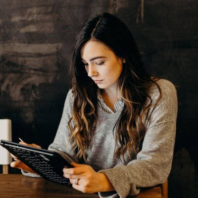 cô gái áo xám cầm máy tính bảng