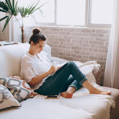 cô gái có thói quen ngồi trên sofa làm việc hạn chế mua sắm online quá mức