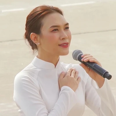 Mỹ Tâm diện áo dài trắng, mái tóc búi gọn, trang điểm nhẹ nhàng, cất giọng hát Tiến Quân Ca trong lễ kỷ niệm Quốc khánh 2/9 tại Quảng trường Ba Đình.