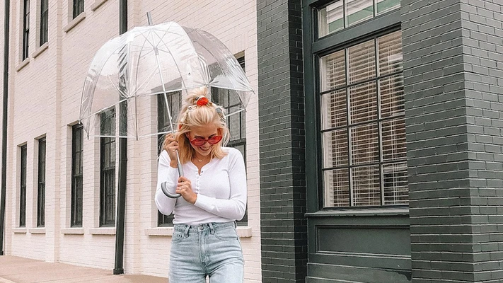 bảo quản quần áo mùa mưa cô gái cầm ô đứng dưới mưa - feature