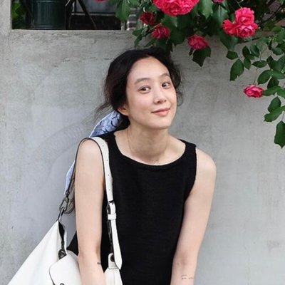 cô gái mang áo đen chụp ảnh bên bờ tường có hoa